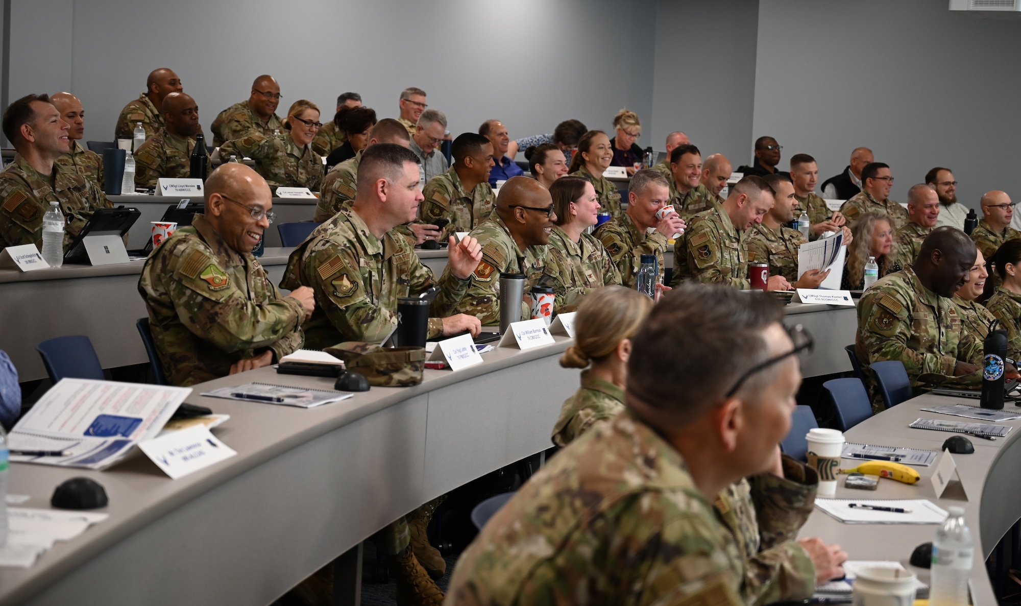 A group of Air Force civilians and military personnel watching a presentation.