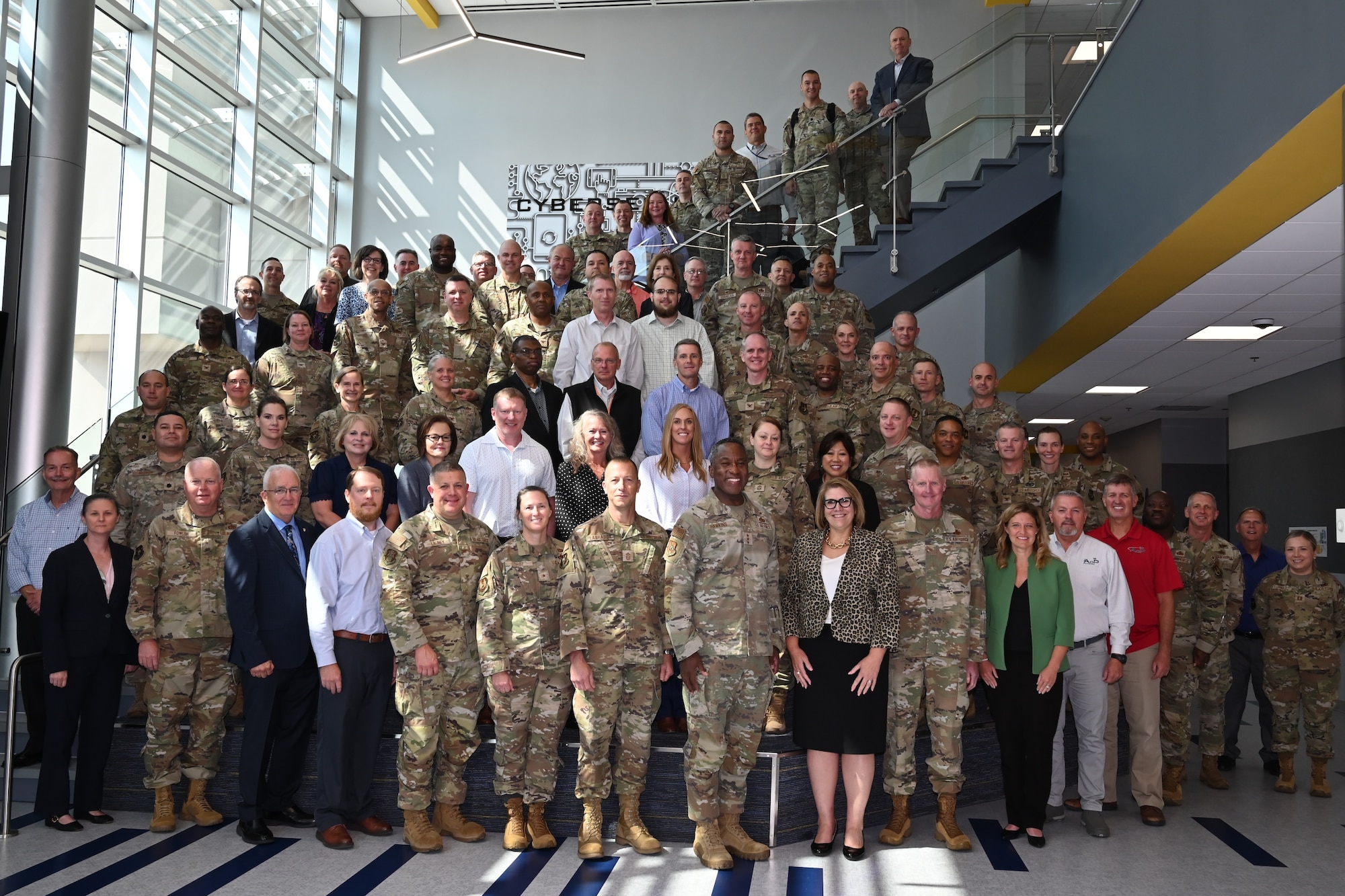 Civilian and uniformed military personnel gather for a group photo.