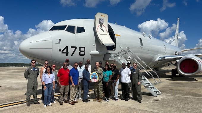 A group of employees stand in front of a P-8 Poseidon.