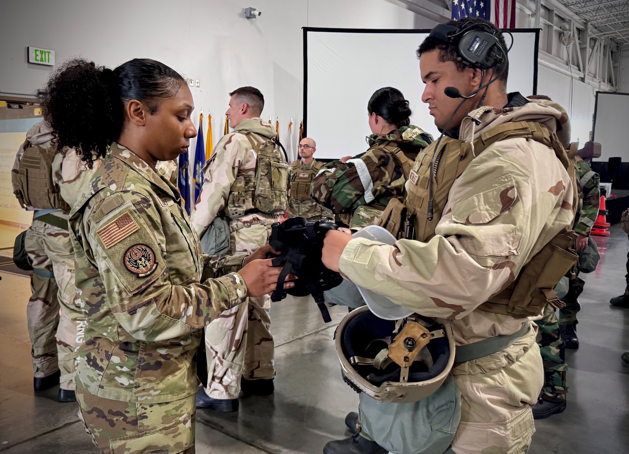 Airman helps out another Airman with their gear