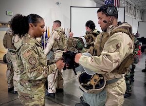 Airman helps out another Airman with their gear