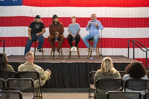 People sitting on a stage in front of an audience.