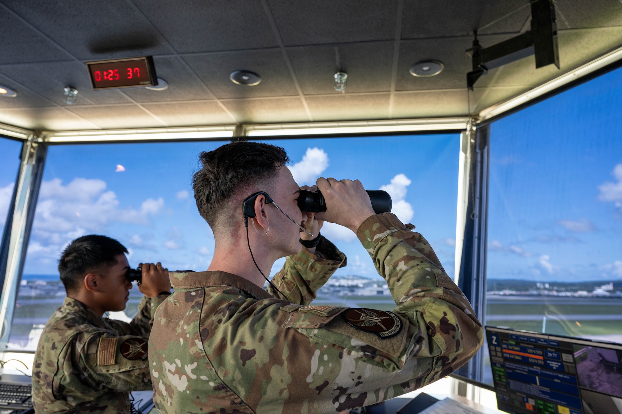 Service members look out the tower with binoculars.