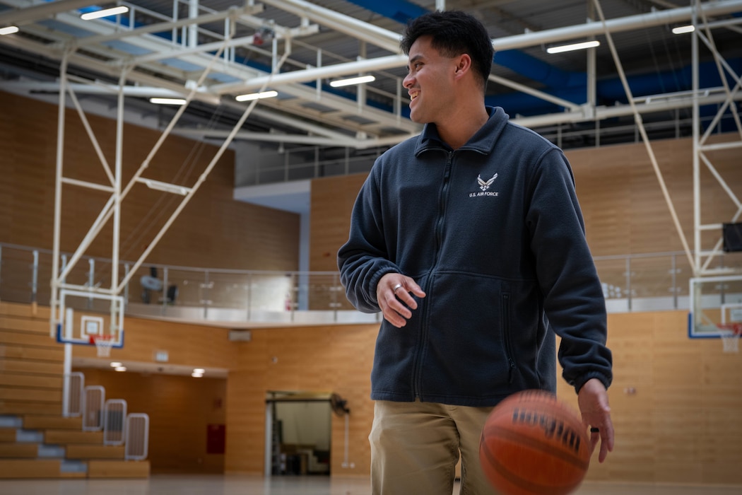 An Airman bounces a basketball in a gym