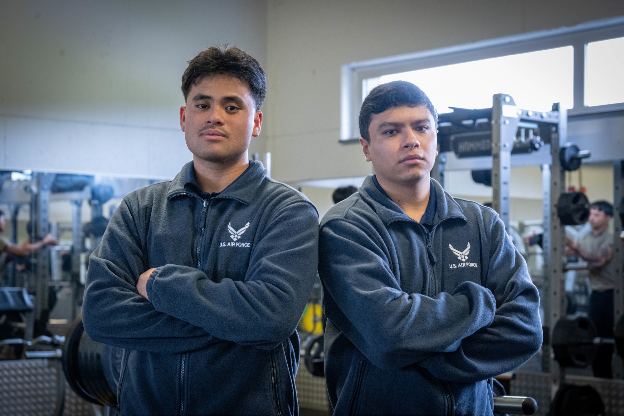 Two Airmen pose back to back for a photo