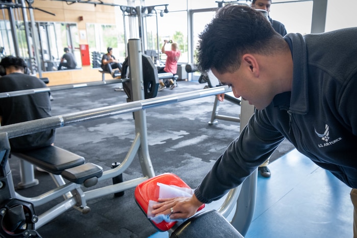 An Airman wipes down gym equipment