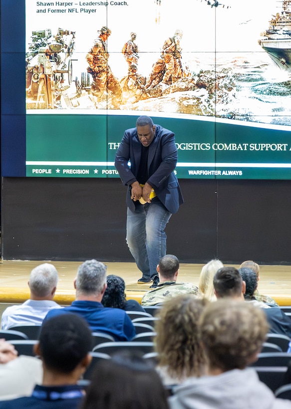 A man bends down to rip several phone books apart on a stage.
