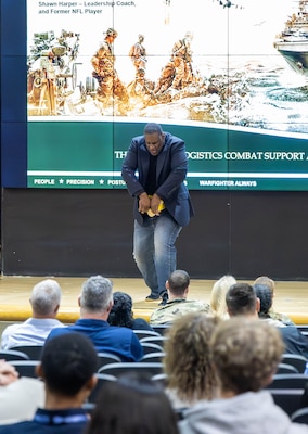 A man bends down to rip several phone books apart on a stage.