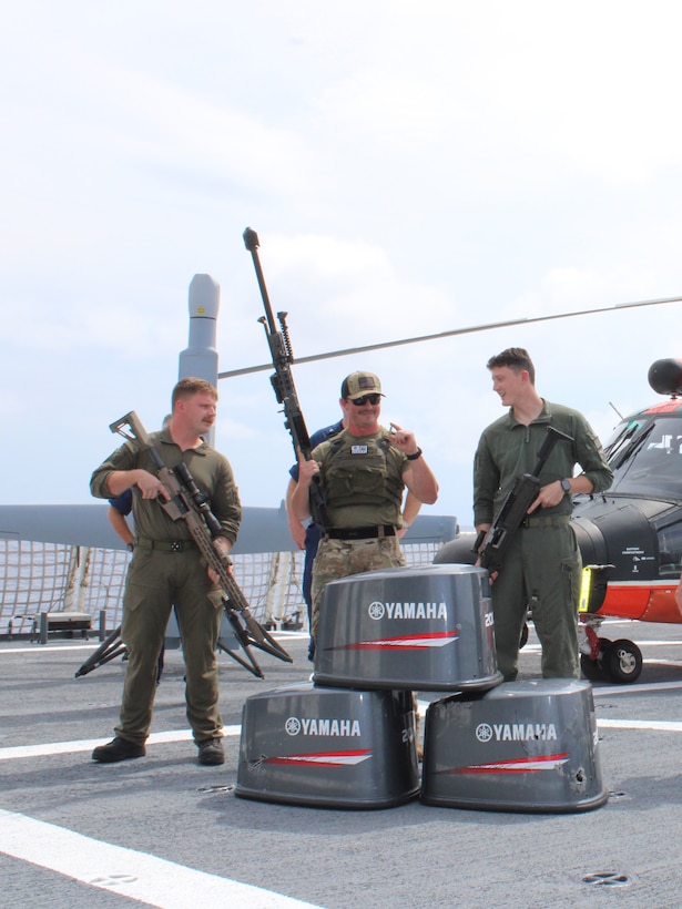 Coast Guard Helicopter Interdiction Tactical Squadron (HITRON) aircrew personnel embarked aboard Coast Guard Cutter Midgett (WMSL 757) display airborne use of force weapons from behind three bullet-damaged outboard engine cowlings in the Eastern Pacific Ocean, Aug. 28, 2025. On Aug. 25, HITRON used airborne use of force to stop the non-compliant vessel, marking the unit’s 1,000th drug interdiction since the unit’s inception in 1999, which resulted in Midgett crew members seizing approximately 3,606 pounds of suspected cocaine worth an estimated $46 million and apprehending six suspected narco-traffickers. (U.S. Coast Guard photo)