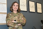 Service member smiles with arms crossed in an office.