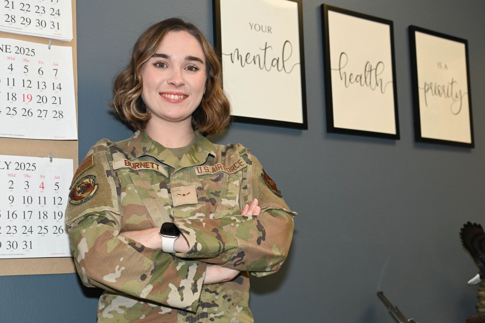 Service member smiles with arms crossed in an office.