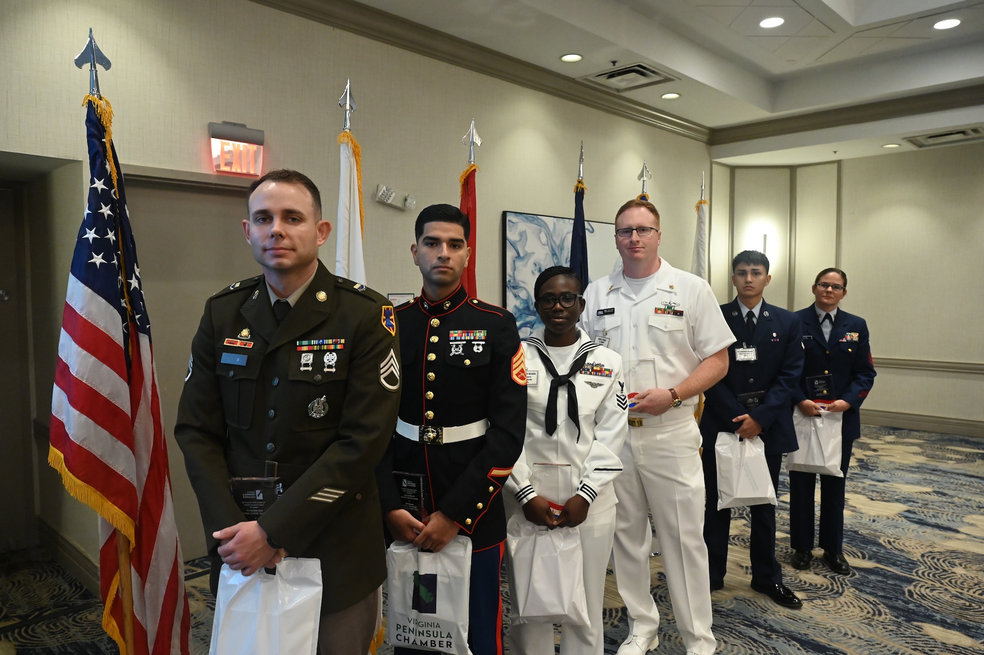 Men and women stand in front of flags.