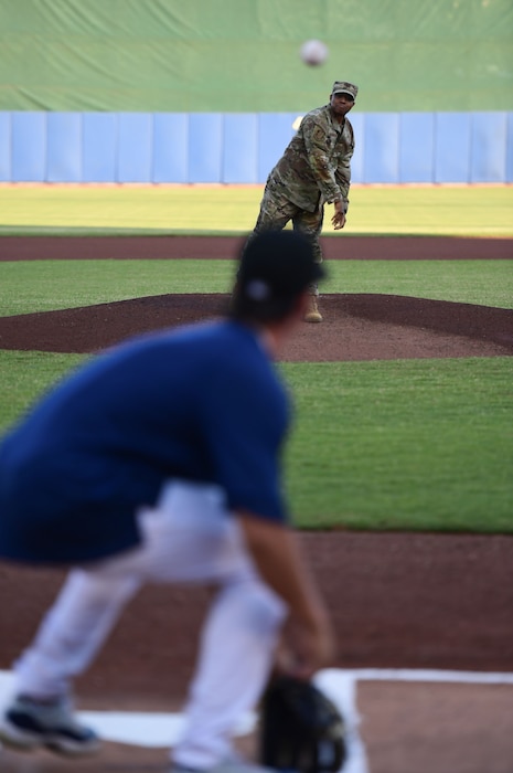 A man throws a baseball towards a catcher