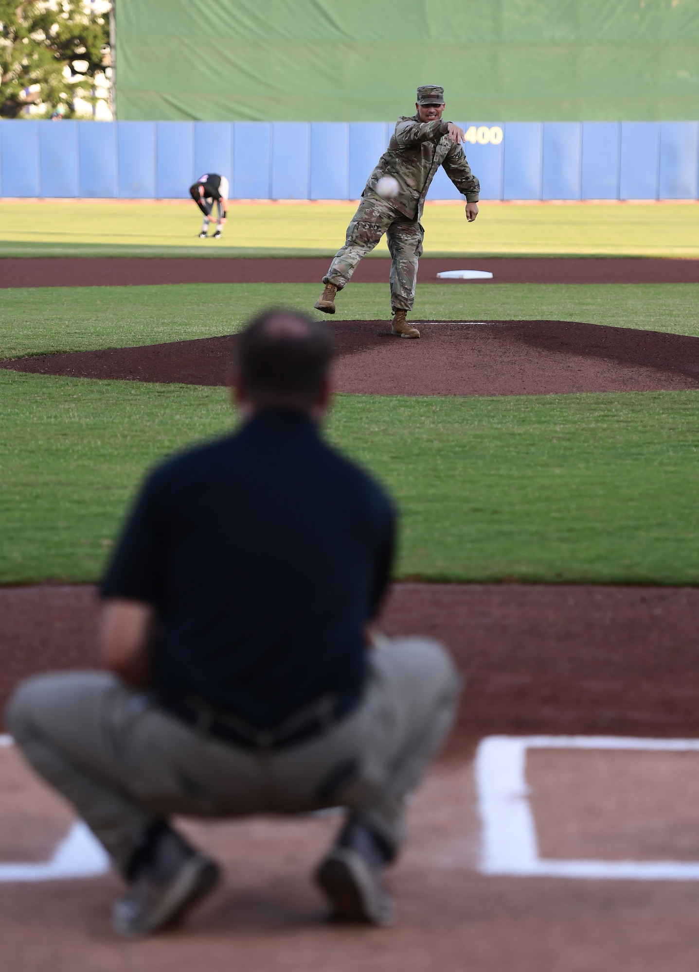 A man throws a baseball towards a pitcher