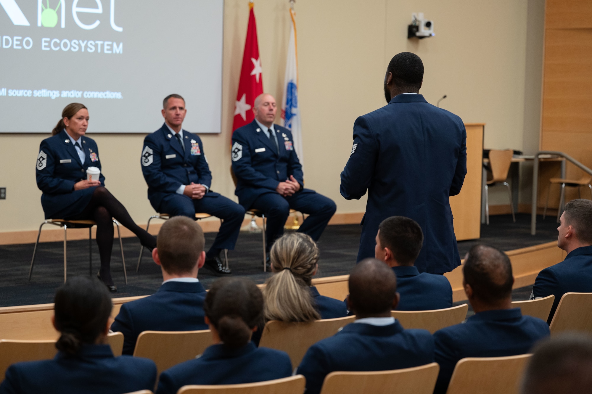 An Airman asks a question in front of a panel.