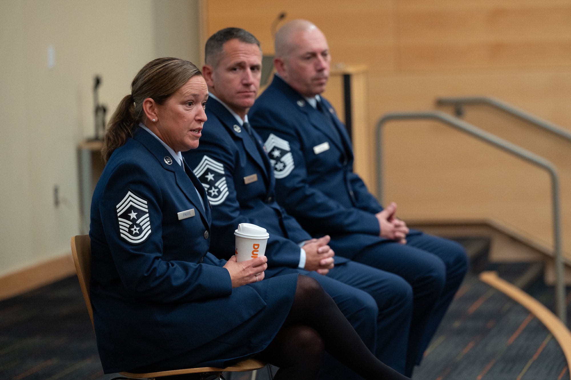 Three Airmen sit in chairs.
