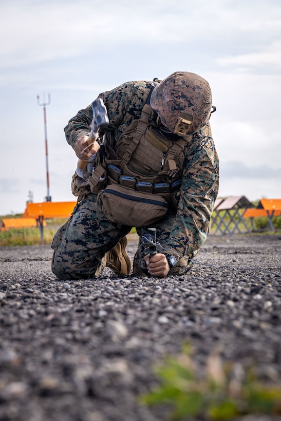 U.S. Marine Corps Lance Cpl. Nathan Llorente, a field radio operator, with 2nd Battalion, 14th Marine regiment, 4th Marine Division, hammers a stake into the ground during High Mobility Artillery Rocket System (HIMARS) as part of ARCTIC EDGE 2025 (AE25), at Cold Bay, Alaska, Aug. 17th, 2025. Specialized Arctic training generates valuable lessons learned for warfighters and enablers ensuring they can execute their assigned missions in any environment. AE25 is a NORAD and U.S. Northern Command-led homeland defense exercise designed to improve readiness, demonstrate capabilities and enhance Joint and Allied Force interoperability in the Arctic. (U.S. Marine Corps Photo by Lance Cpl. Edward Spears)