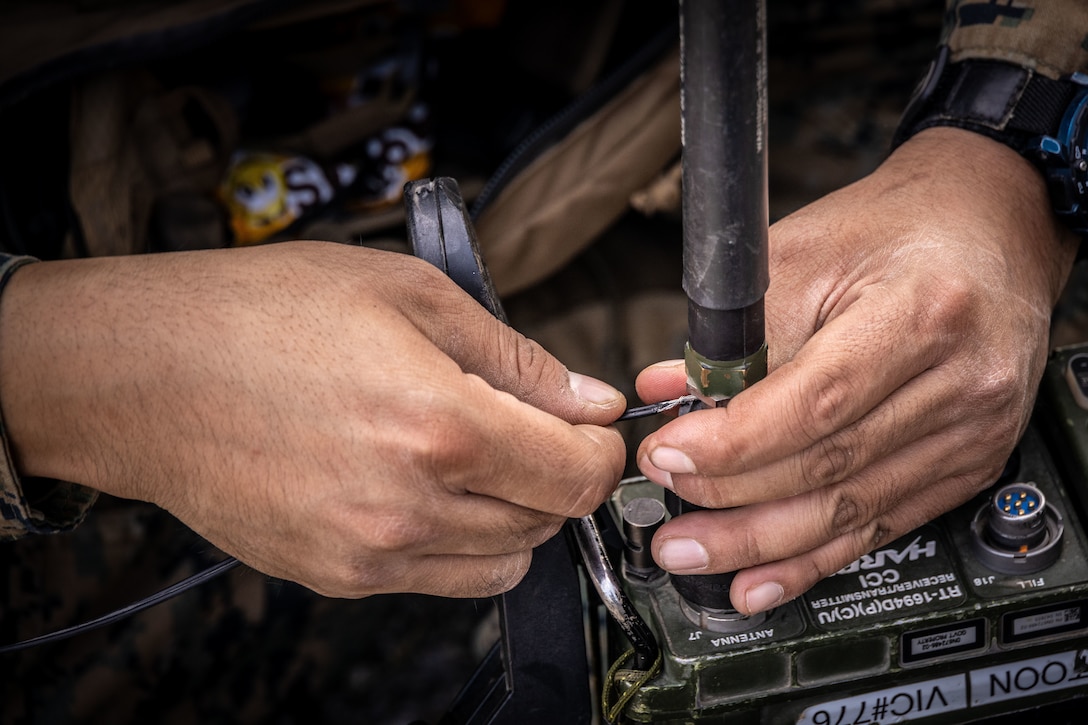 U.S. Marine Corps Lance Cpl. Kevin Villanueva, a field radio operator, with 2nd Battalion, 14th Marine regiment, 4th Marine Division, connects a wire to radio systems during High Mobility Artillery Rocket System (HIMARS) training as part of ARCTIC EDGE 2025 (AE25), at Cold Bay, Alaska, Aug. 17th, 2025. Specialized Arctic training generates valuable lessons learned for warfighters and enablers ensuring they can execute their assigned missions in any environment. AE25 is a NORAD and U.S. Northern Command-led homeland defense exercise designed to improve readiness, demonstrate capabilities and enhance Joint and Allied Force interoperability in the Arctic. (U.S. Marine Corps Photo by Lance Cpl. Edward Spears)