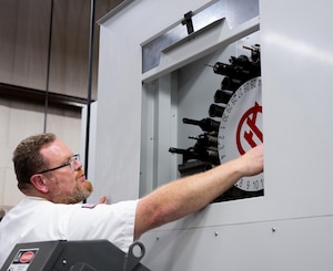 David Mercer, 47th Maintenance Directorate, fabrication supervisor, adjusts tooling on a Computer Numerical Control (CNC) machine at Laughlin Air Force Base, Texas, Sept. 10, 2025. The unit integrates CNC machining with 3D scanning and additive manufacturing to streamline part production and support pilot training missions. (U.S. Air Force photo by Airman 1st Class Harrison Sullivan)