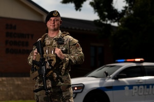 Man poses for a picture while standing in front of police car.
