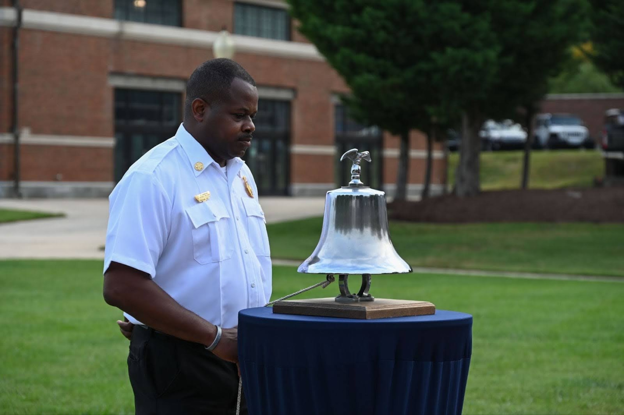 Chief Darius Hawkins, district fire chief for the Naval District Washington Fire Department, tolls a bell during a 9/11 remembrance ceremony at Joint Base Anacostia-Bolling, Washington, D.C., Sep. 11, 2025.
