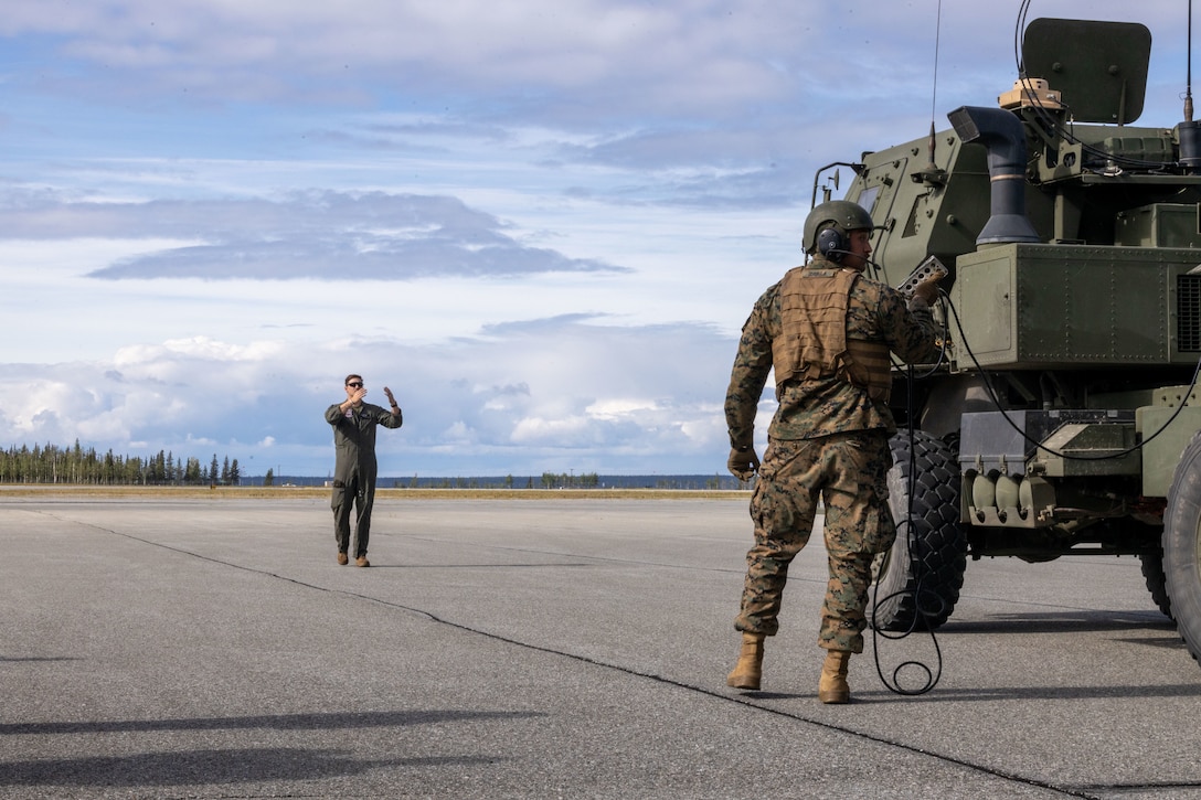 U.S. Marine Corps Sgt. John Williamson, a loadmaster, with Marine Aerial Refueler Squadron 234 (VMGR-234), 4th Marine Aircraft Wing, ground guide a High Mobility Artillery Rocket System (HIMARS) during ARCTIC EDGE 2025 (AE25) at Joint Base Fort Greenly, Alaska, Aug. 22, 2025. Specialized Arctic training generates valuable lessons learned for warfighters and enablers ensuring they can execute their assigned missions in any environment. AE25 is a NORAD and U.S. Northern Command-led homeland defense exercise designed to improve readiness, demonstrate capabilities and enhance Joint and Allied Force interoperability in the Arctic. (U.S. Marine Corps Photo by Lance Cpl. Edward Spears.)