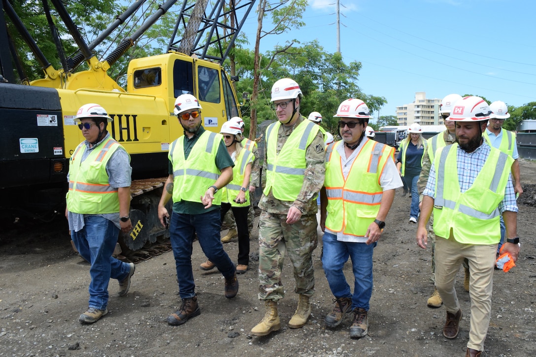 San Juan, Puerto Rico, September 03, 2025 - Jorge Rivera-Cruz (left), Structural Engineer & Technical Lead in the Engineering Division, Caribbean District walks alongside Brig. Gen. Zachary L. Miller (center), USACE South Atlantic Division Commanding General during a Caño Martín Peña Ecosystem Restoration Project visit. Jorge just completed his dissertation that involved testing three full-scale reinforced concrete frame sub-assemblages in the laboratory to simulate the removal of an interior column and assess the progressive collapse resistance of perimeter frames. Due to his research, the American Concrete Institute (ACI) revised the structural integrity requirements for beam reinforcement in the 2025 edition of ACI 318. Specifically, the Code now mandates reduced maximum spacing for closed stirrups to enhance compliance with seismic design criteria. As a result, seismic designers of concrete beams—both in the United States and internationally—will now rely on these updated ACI provisions to guide safer and more resilient structural designs.
