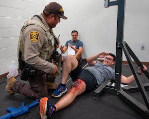 A Val Verde Sheriff officer checks a wounded hostage during an exercise at Laughlin Air Force Base, Texas, Sept. 4, 2025. Officers breached the room and neutralized the threat, allowing them to check on the hostages and give first aid. (U.S. Air Force photo by Staff Sgt. Nicholas Larsen)