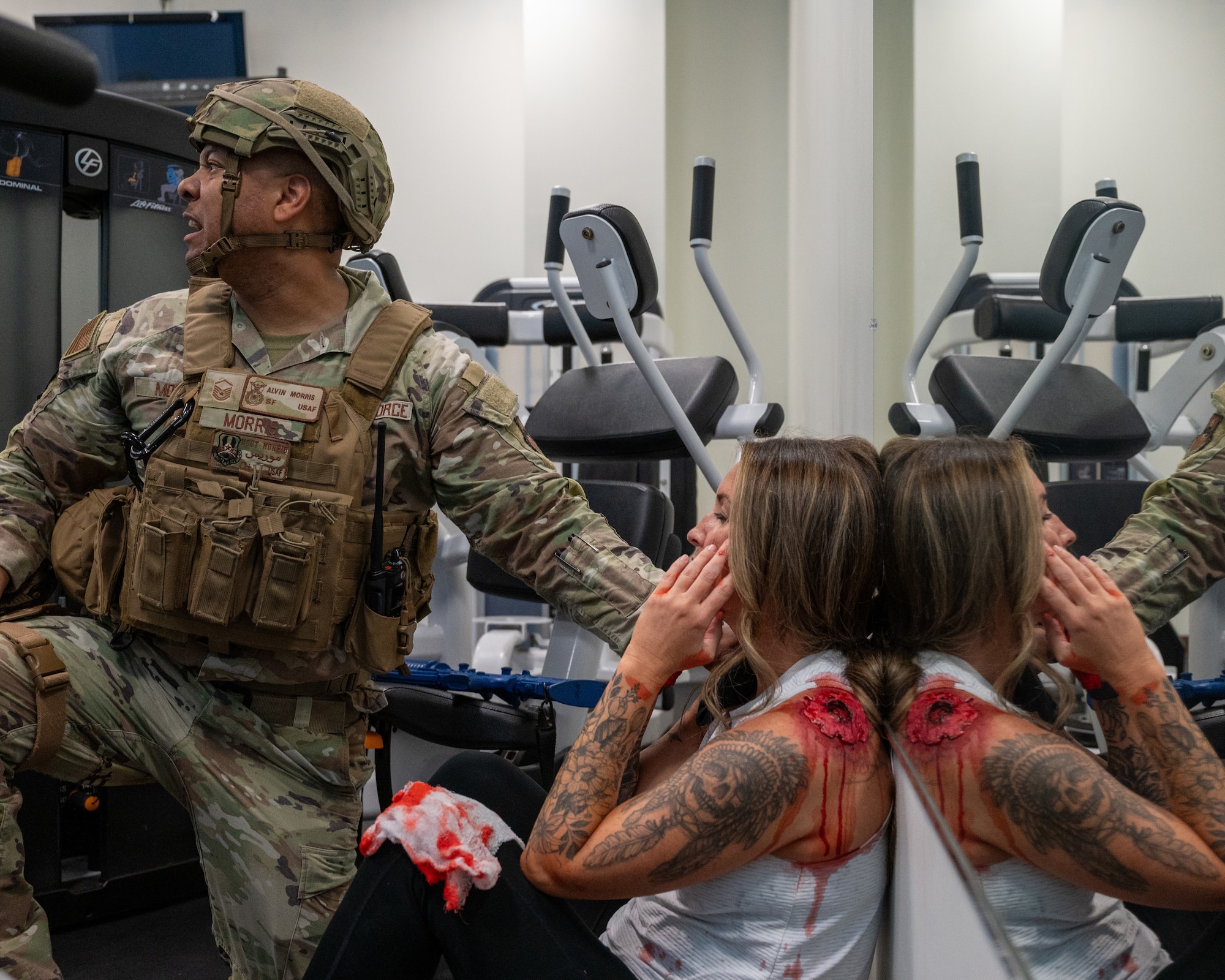 U.S. Air Force Master Sgt. Alvin Morris, 47th Security Forces Squadron superintendent logistics and readiness, left, calls for more aid while checking on a wounded hostage at an exercise at Laughlin Air Force Base, Texas, Sept. 4, 2025. Security Forces personnel gave first aid to wounded hostages once the hostage taker was eliminated. (U.S. Air Force photo by Staff Sgt. Nicholas Larsen)