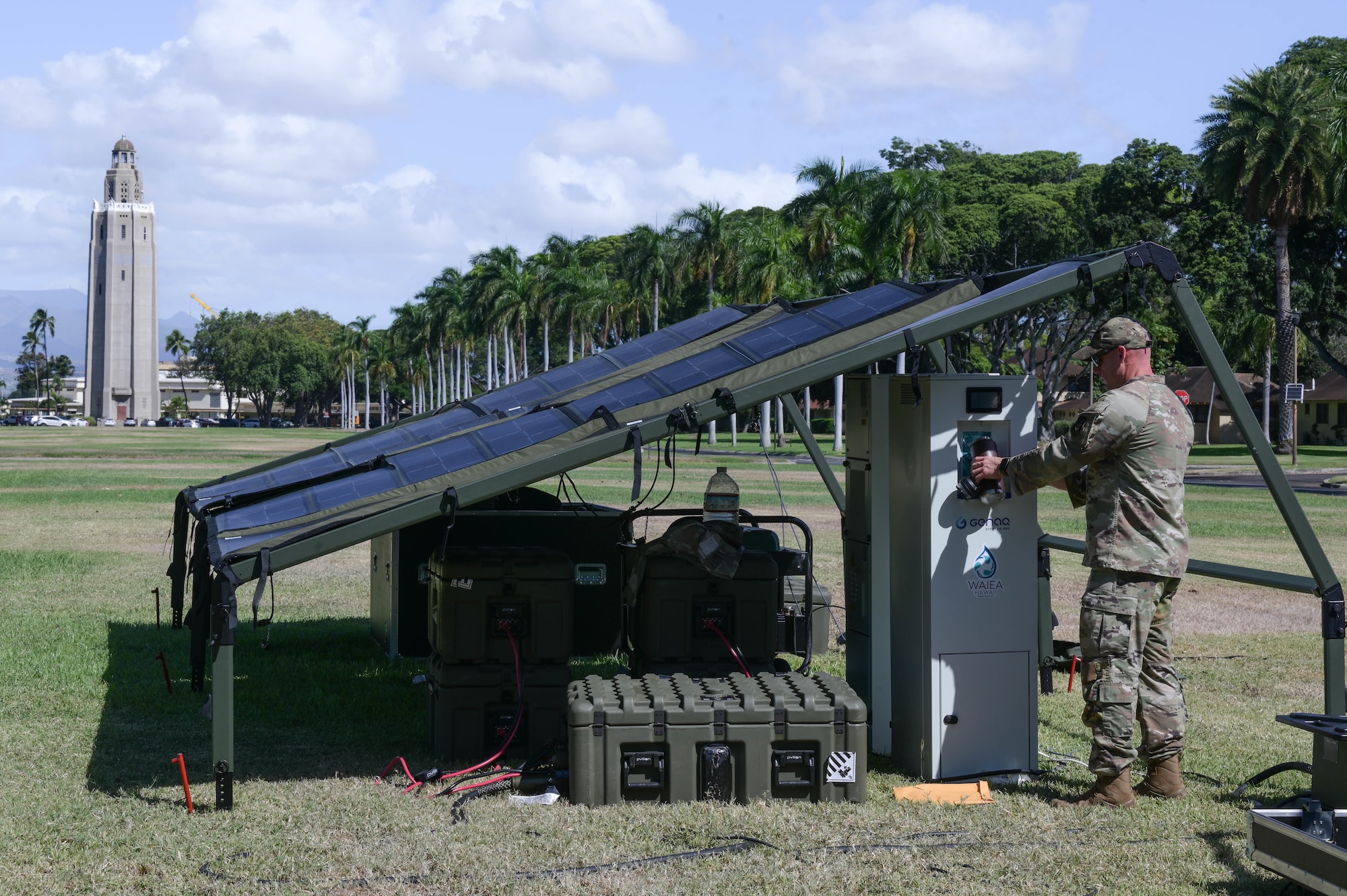 Solar powered tent in a field and an Airman using a generator to receive water.