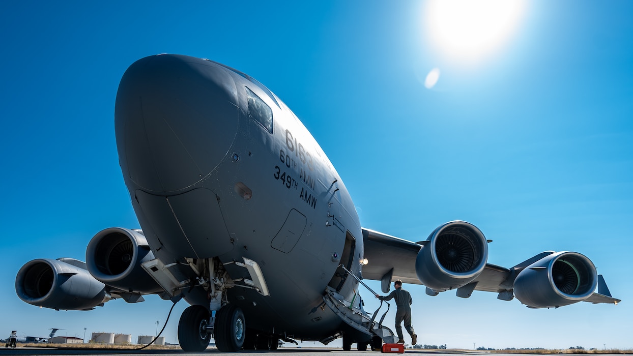 A pilot begins to ascend the stairs of a C-17