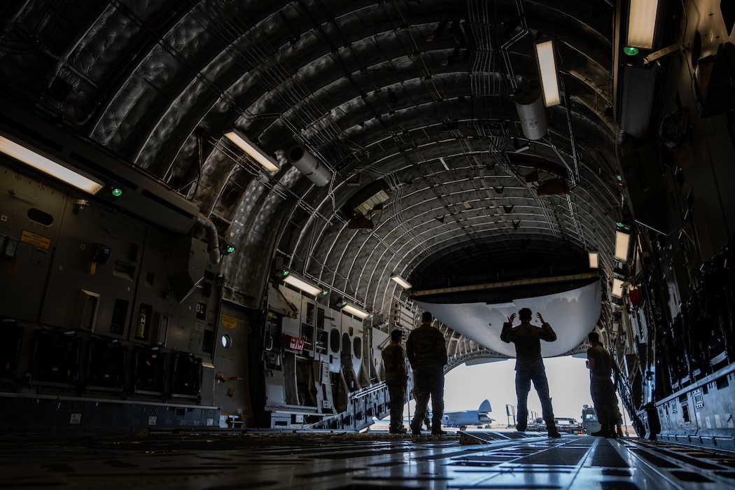 Airmen stand in the cargo bay of a C-17 during loading