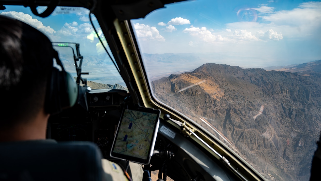 An Airman pilots a C-17 with mountains visible