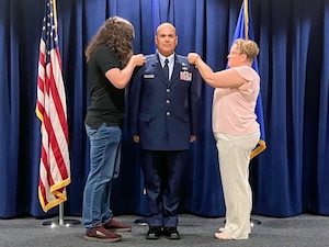 CWO2 Dell stands at attention while his family members pin on his new warrant officer 2 rank.