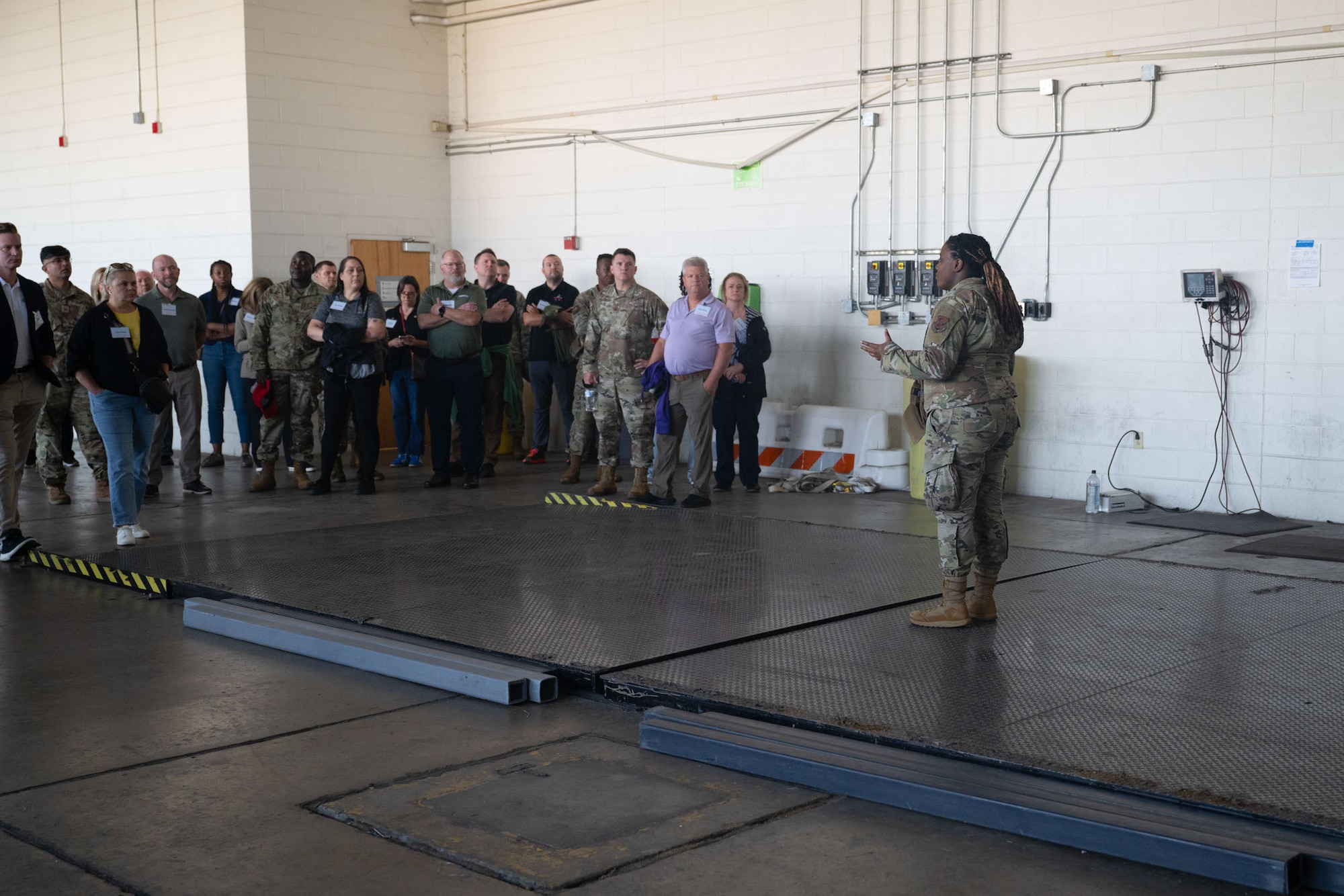 SSgt Mahmood, right, talks to a large group of civilian employers and military personnel in a hangar during a base tour
