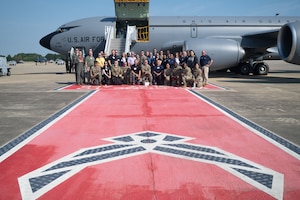Group of civilian employers and military personnel posing for a group photo with a red walkway and Air Force symbol, KC-135 in the background