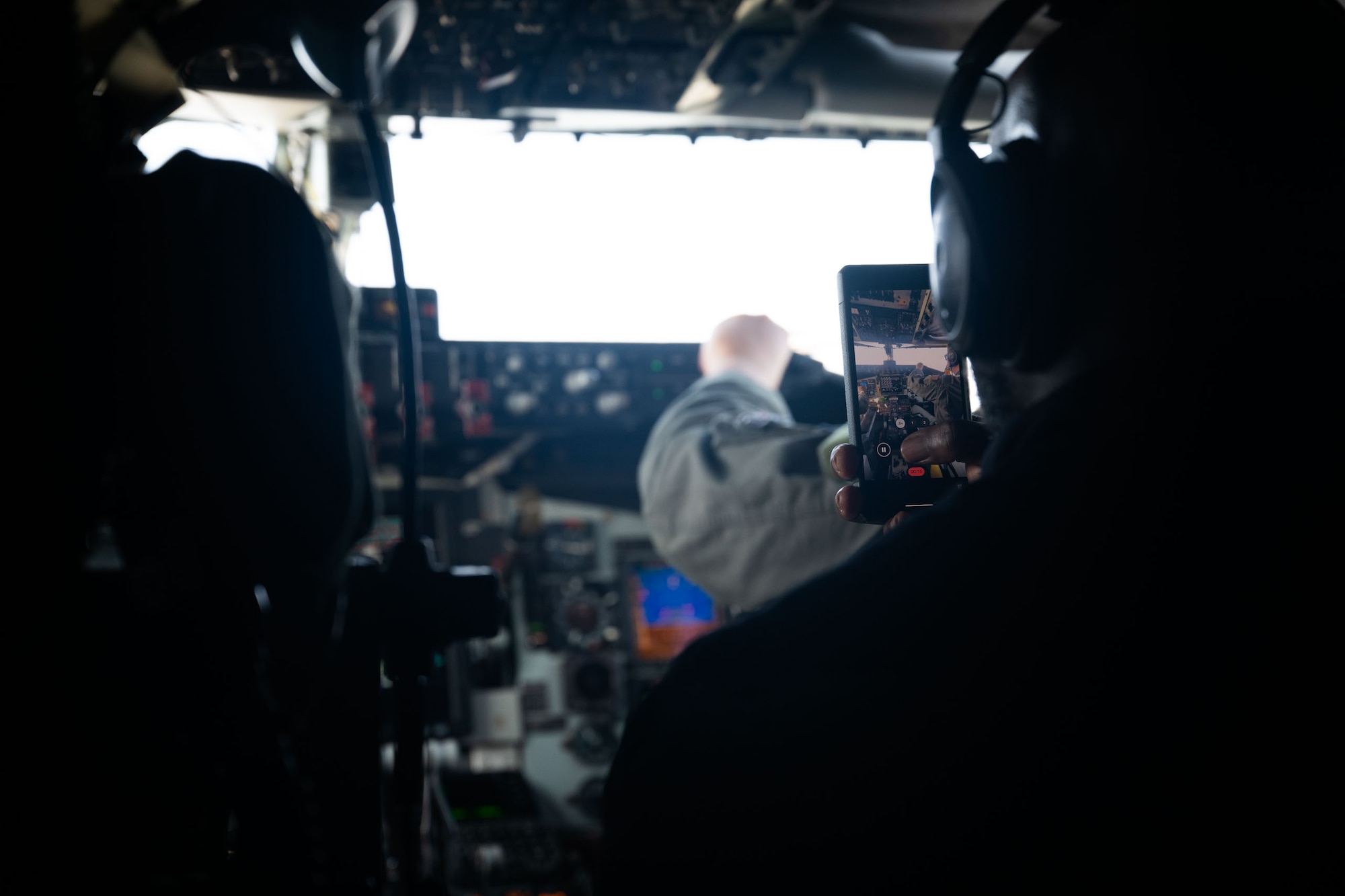 View of cell phone over someone's shoulder, taking photos in a KC-135 cockpit