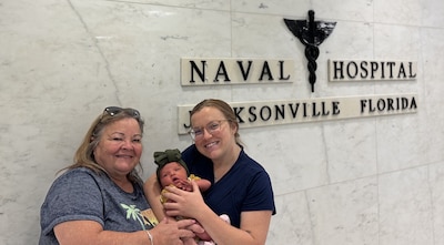Lt. Danielle Acosta, her mother Tina Cox, and Dahlia, the newest addition to the family, at the very place where their generational story began. Acosta is currently a Naval Hospital Jacksonville Labor and Delivery nurse, who was born at the same hospital in 1998 to her mother, also a U.S. Navy Labor and Delivery nurse.