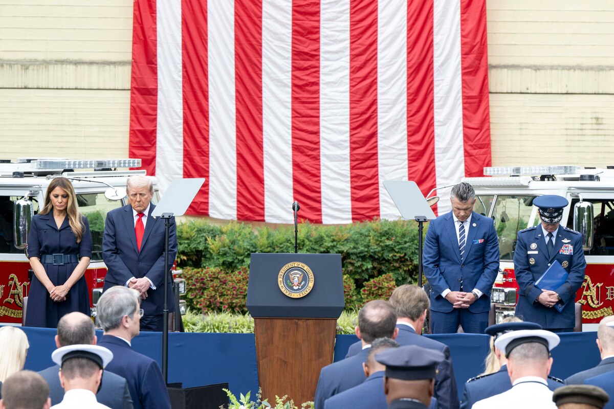 The president, the first lady, the secretary of war and the chairman bow their heads while standing on stage.