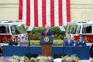 The president speaks at a podium as the defense secretary and chairman sit the right and the first lady on the left.