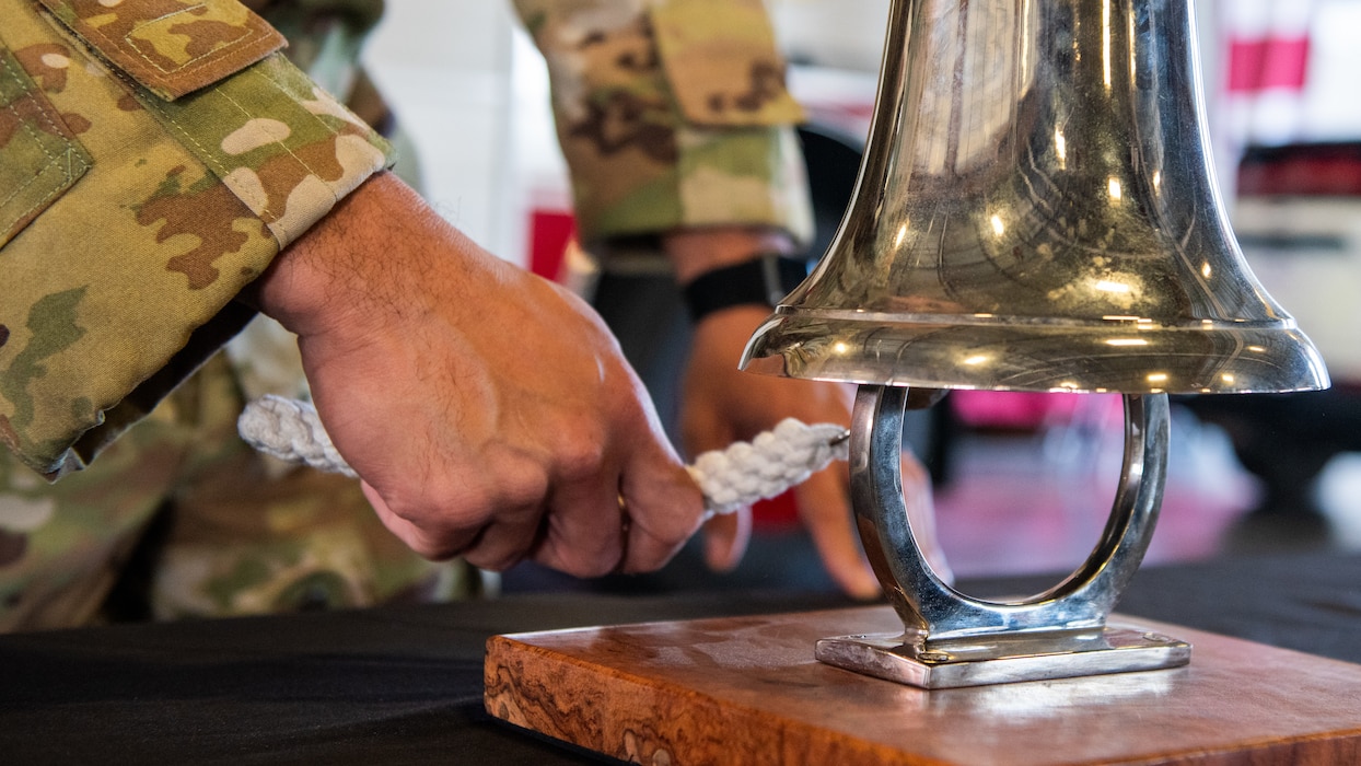 An Airman's hand ringing a bell