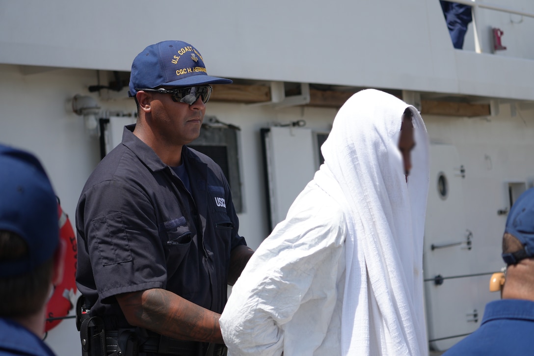 A Coast Guard Cutter Heriberto Hernandez crewmember assists one of 66 aliens during their repatriation process at San Pedro de Macoris, Dominican Republic, Sept. 11, 2025.  The crew of the cutter Heriberto Hernandez interdicted an unlawful migration voyage vessel with the alien group in Mona Passage waters off Puerto Rico, Sept. 9, 2025. (U.S. Coast Guard photo)