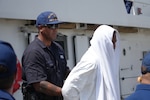 A Coast Guard Cutter Heriberto Hernandez crewmember assists one of 66 aliens during their repatriation process at San Pedro de Macoris, Dominican Republic, Sept. 11, 2025.  The crew of the cutter Heriberto Hernandez interdicted an unlawful migration voyage vessel with the alien group in Mona Passage waters off Puerto Rico, Sept. 9, 2025. (U.S. Coast Guard photo)