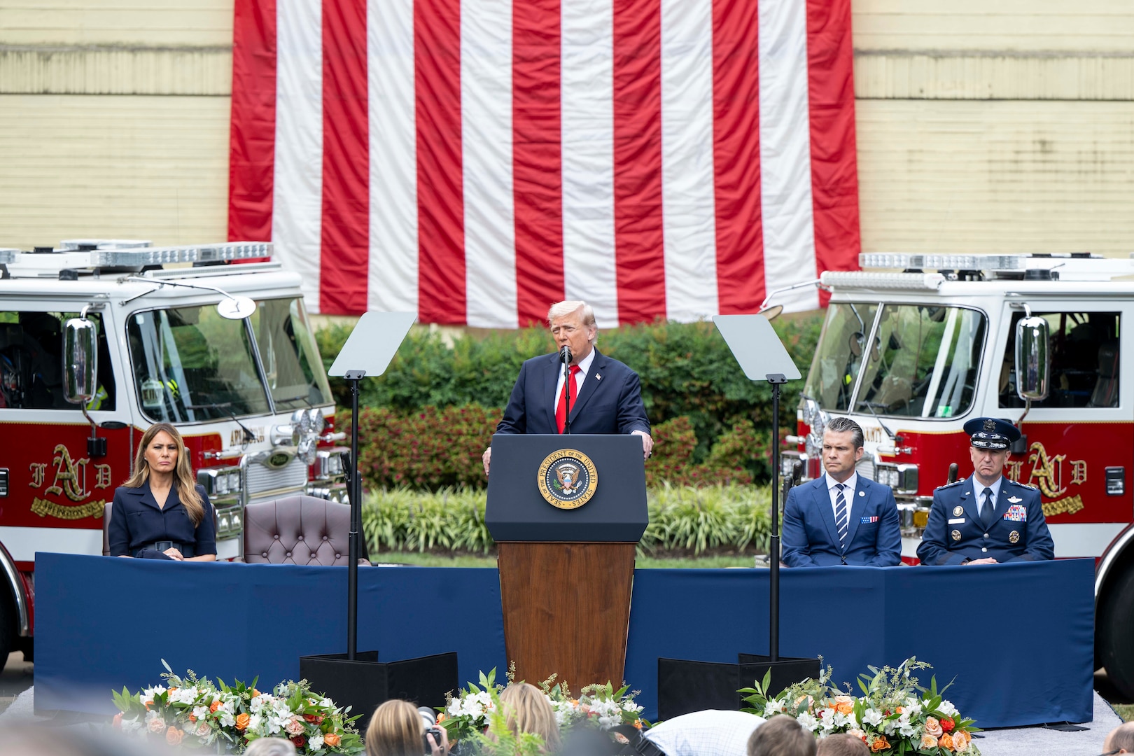 The president speaks at a podium as the defense secretary and chairman sit the right and the first lady on the left.