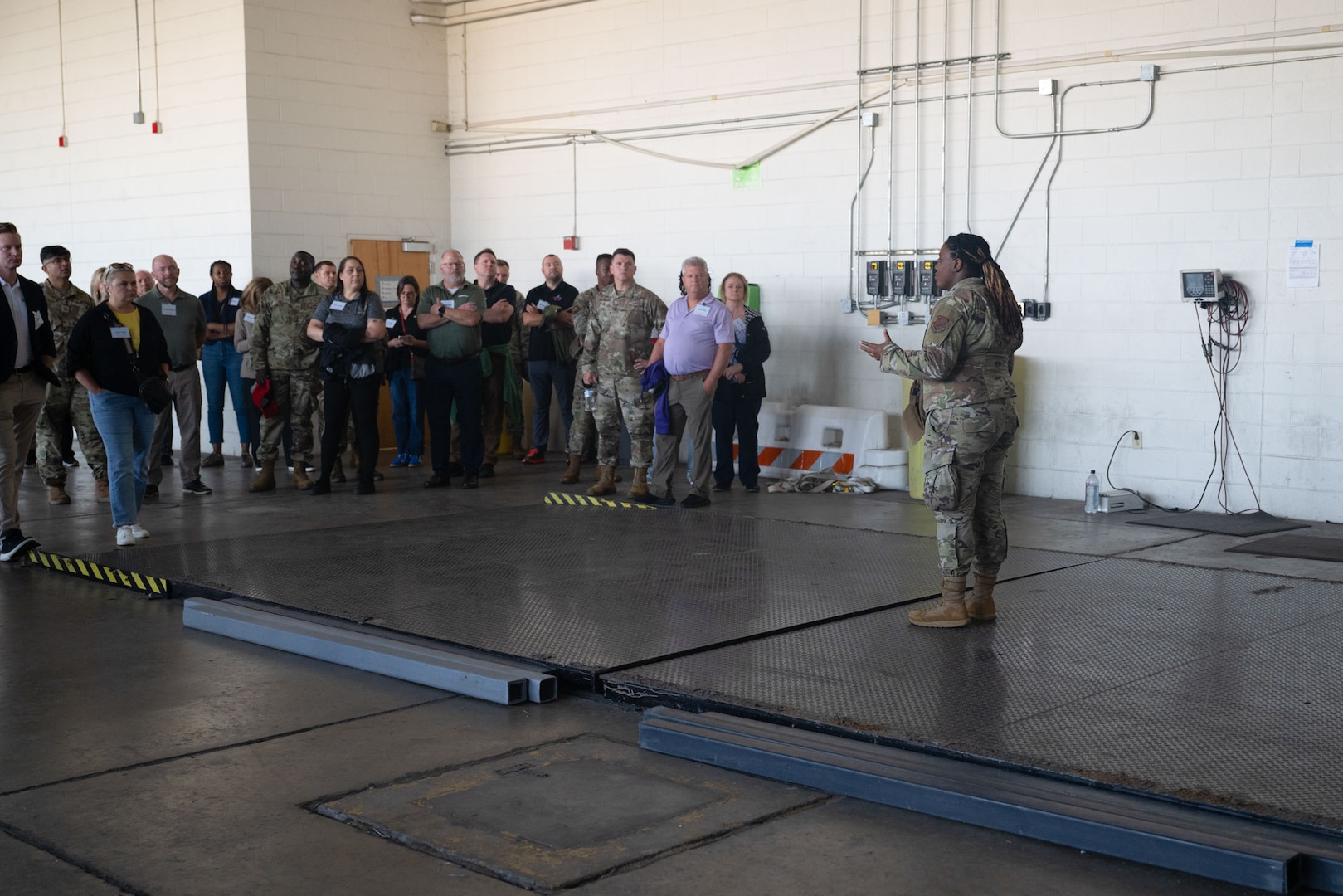 SSgt Mahmood, right, talks to a large group of civilian employers and military personnel in a hangar during a base tour