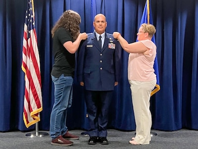 CWO2 Dell stands at attention while his family members pin on his new warrant officer 2 rank.