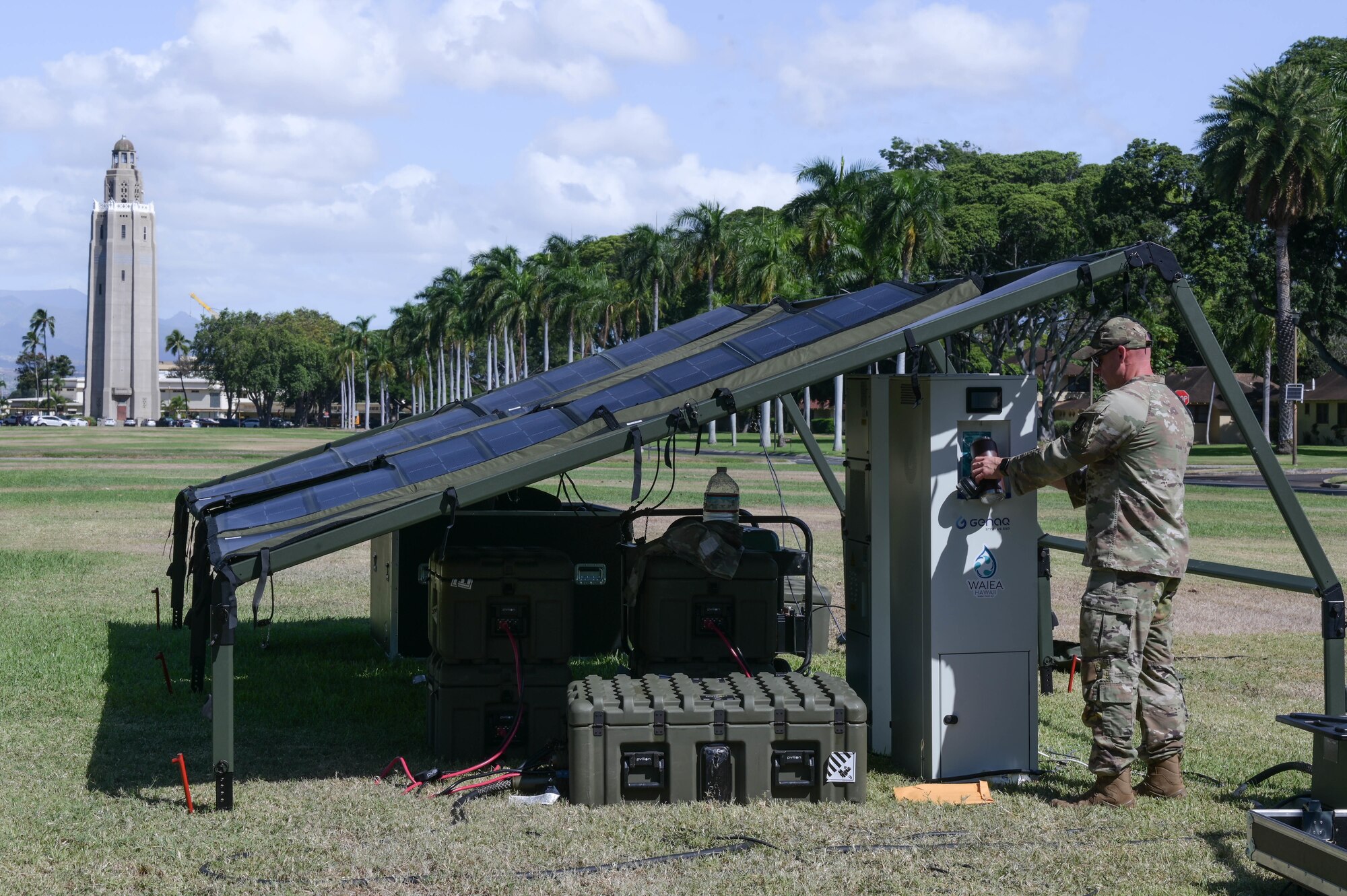 Solar powered tent in a field and an Airman using a generator to receive water.