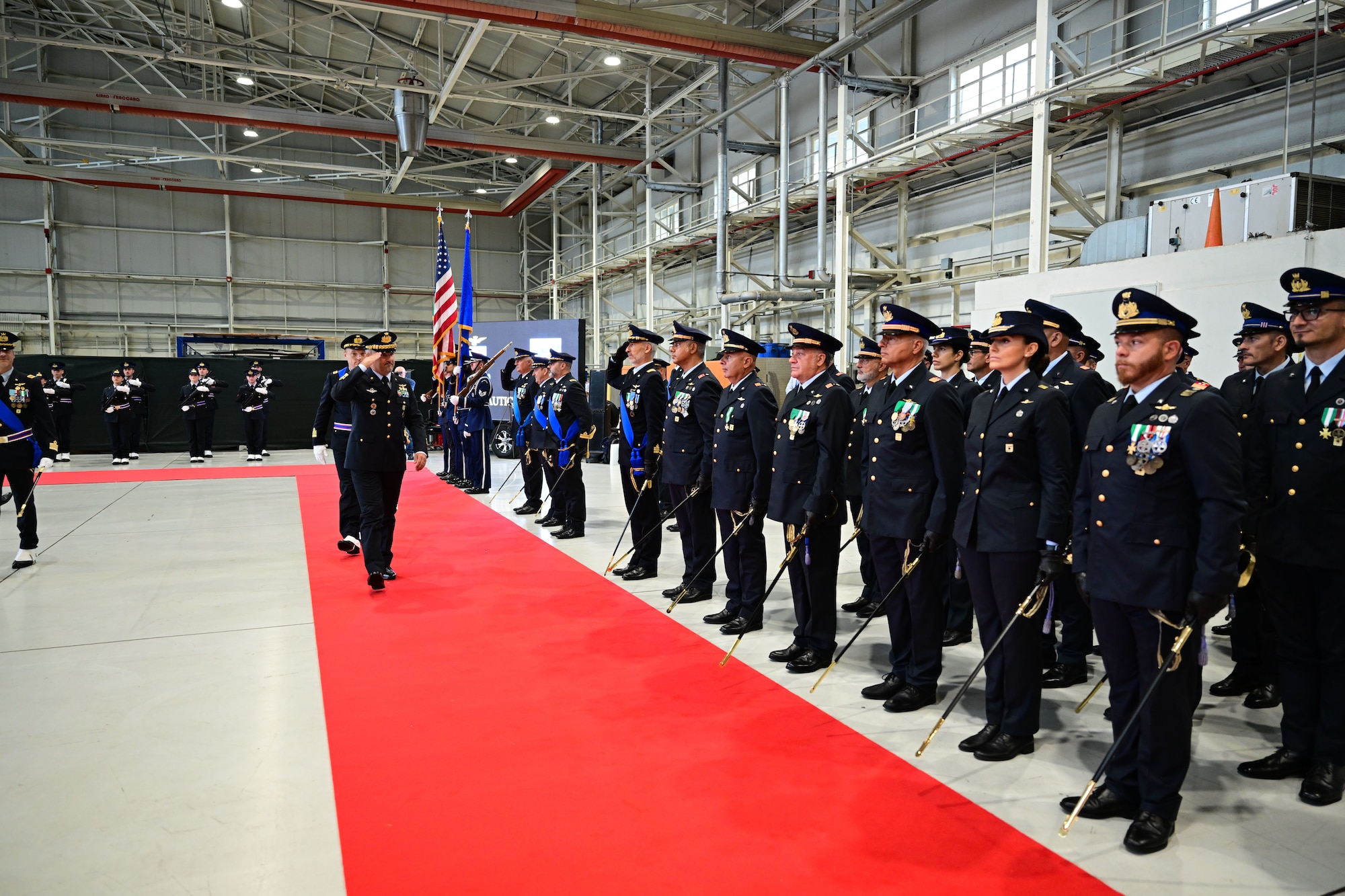 Members of the Italian Air Force stand in formation while a general renders a salute.