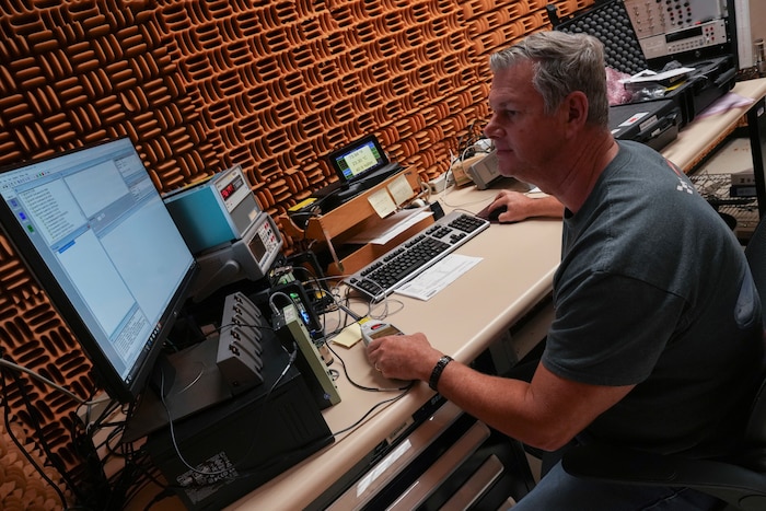 Man sits at desk, calibrating noise detector