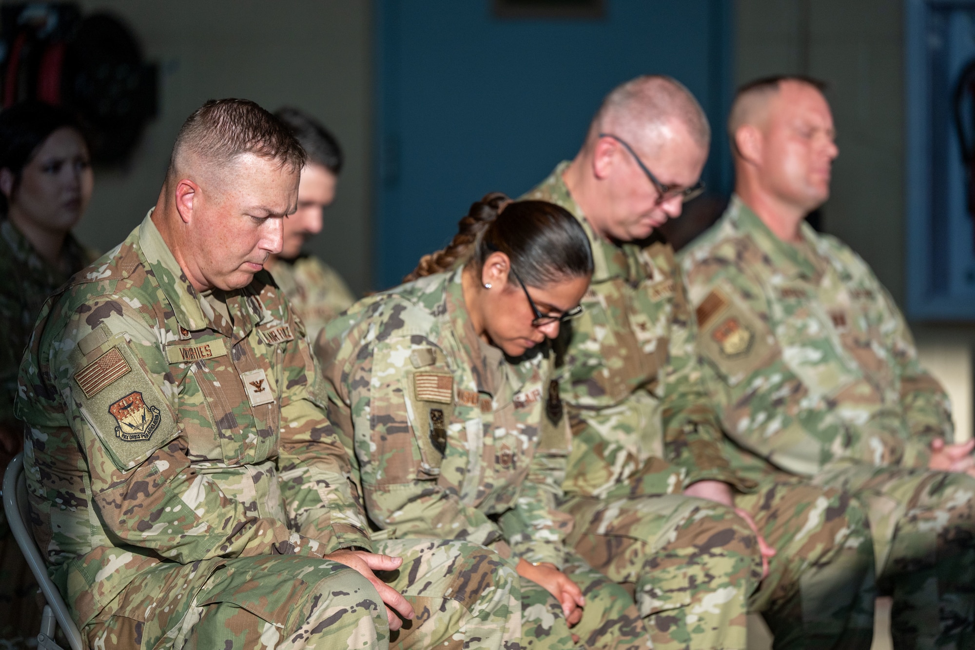 Four Airmen sitting down with their heads bowed.